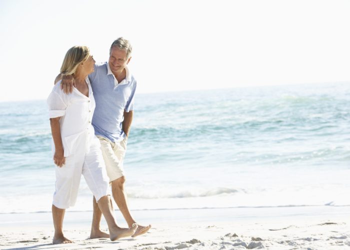Senior Couple Walking Along Beach
