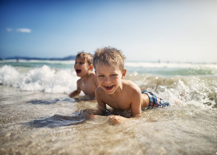 Little boys lying on beach in sea and laughing